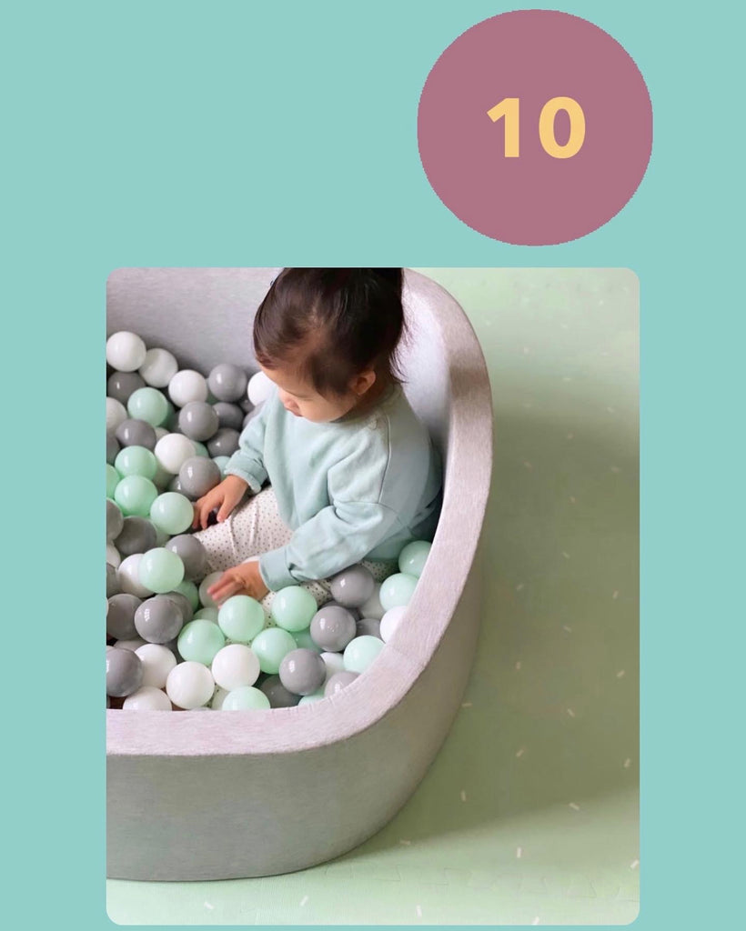 Kiara Lai Confetti Playmat in mint baby playing in ball pit
